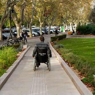 Informació d'adaptacions - Imatge d'un xic en cadira de rodes eixint de la Universitat cap a Blasco Ibañez
