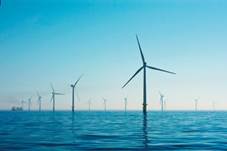 Un molino de viento junto a un cuerpo de agua
Descripción generada automáticamente con confianza media