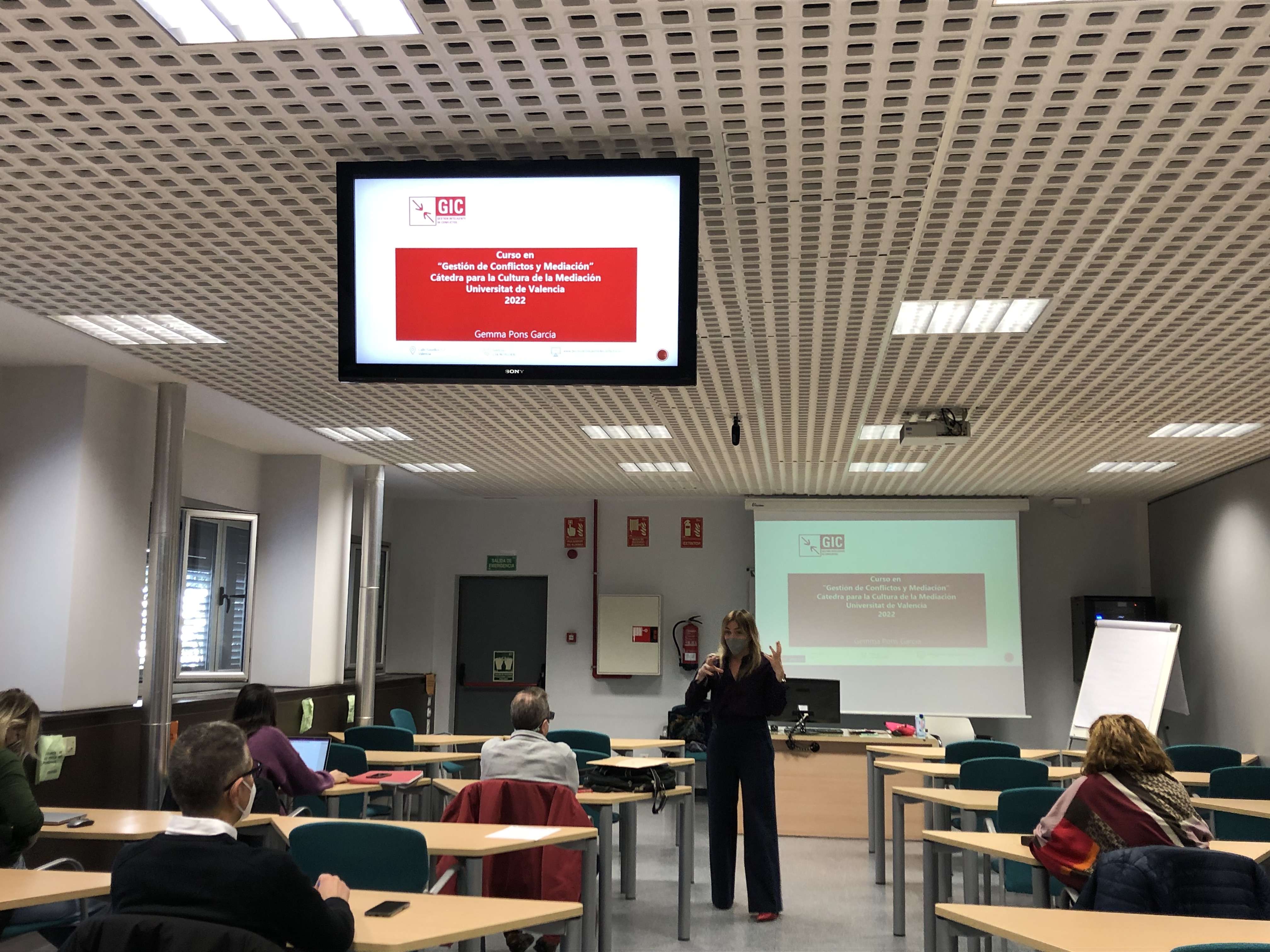 Foto durant una classe amb una professora parlant.