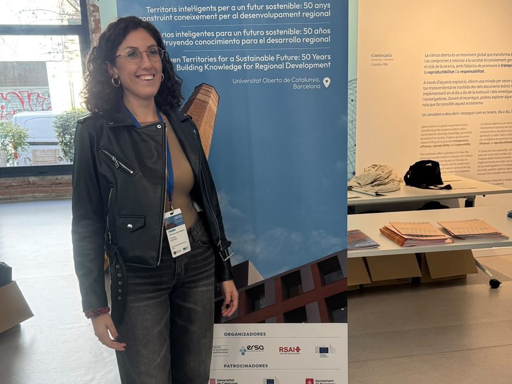 Cristina Caldareri en el congreso, ante el cartel del evento.