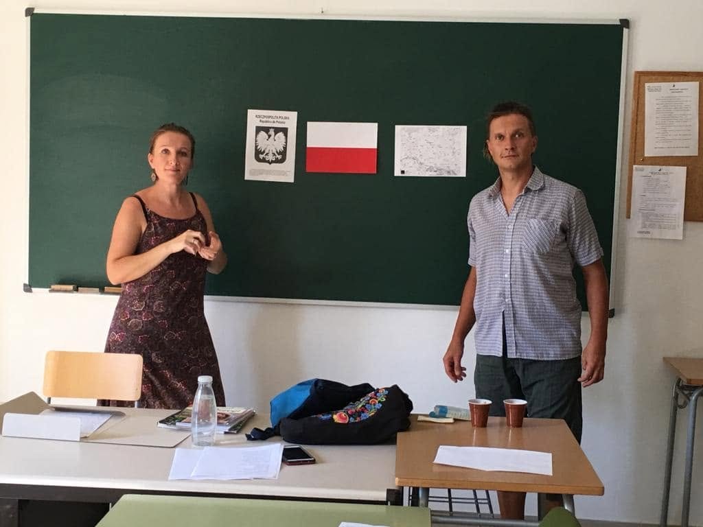 Aula del festival con la bandera de Polonia y dos personas impartiendo la clase