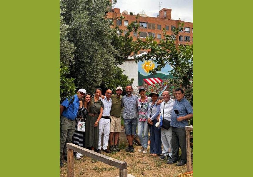 Un grup d'homes i dones, docents, posa en la visita d'un hort entre arbres.