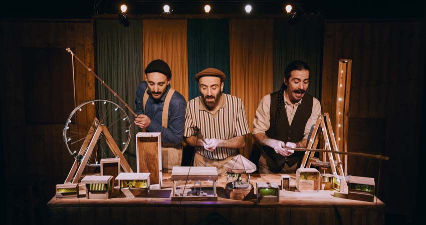 Tres hombres detrás de una mesa con la maqueta de una feria