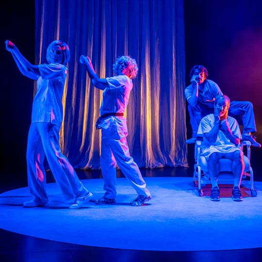 Quatre persones en l'escenari, tres dempeus i una en cadira de rodes