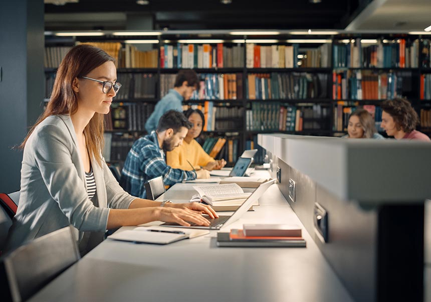 Jove estudiant a la biblioteca amb un portàtil