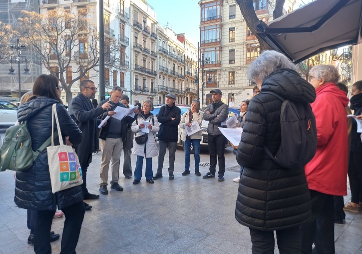 Un grup de persones en un carrer de València llegint un text - imatge 0