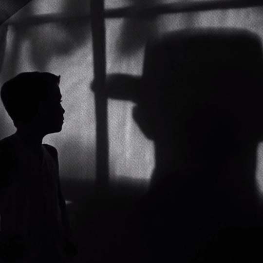 A boy in profile and a man with a hat on his back