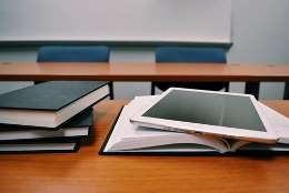 Imatge de llibres oberts i una tablet damunt d'una taula