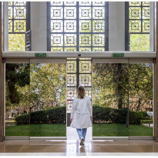 Dona eixint per una porta acristalada amb un Vinil amb una imatge d'un jardí