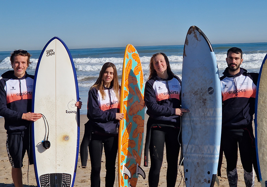 deportistas de la UV posando con sus tablas de surf en la playa