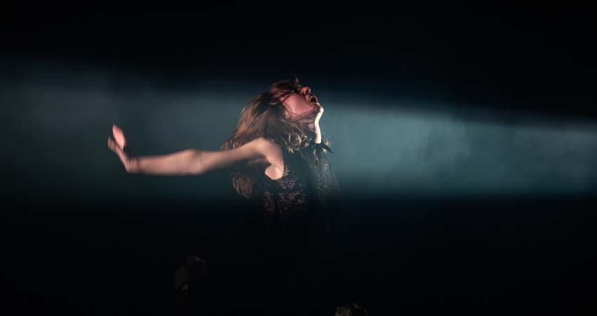 Una mujer iluminada por un foco actuando