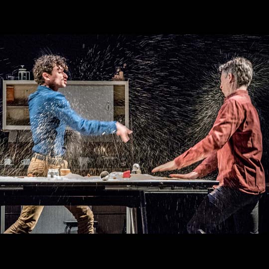 Two men on stage throwing water on each other