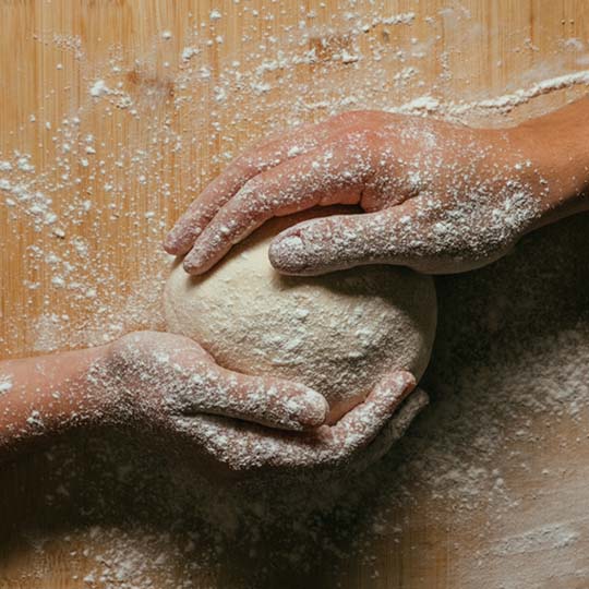 Two hands picking up a bread dough