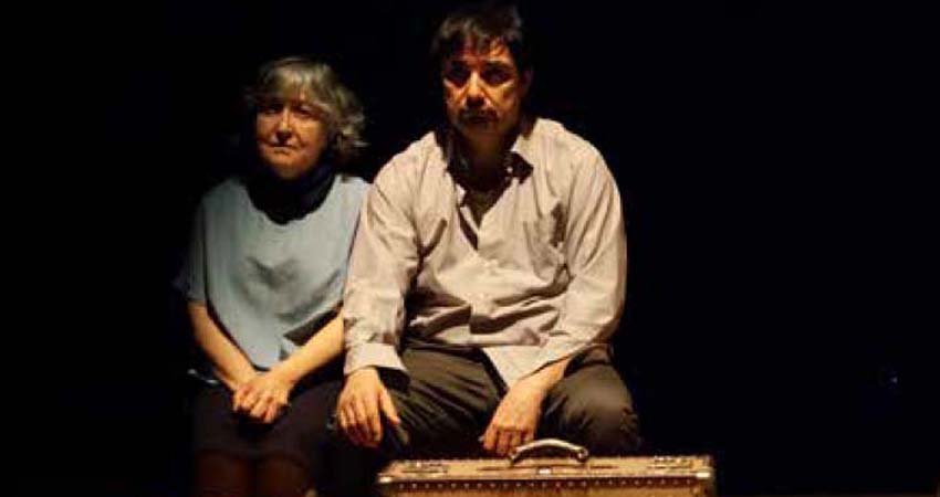 A woman and a man sitting in front of some suitcases