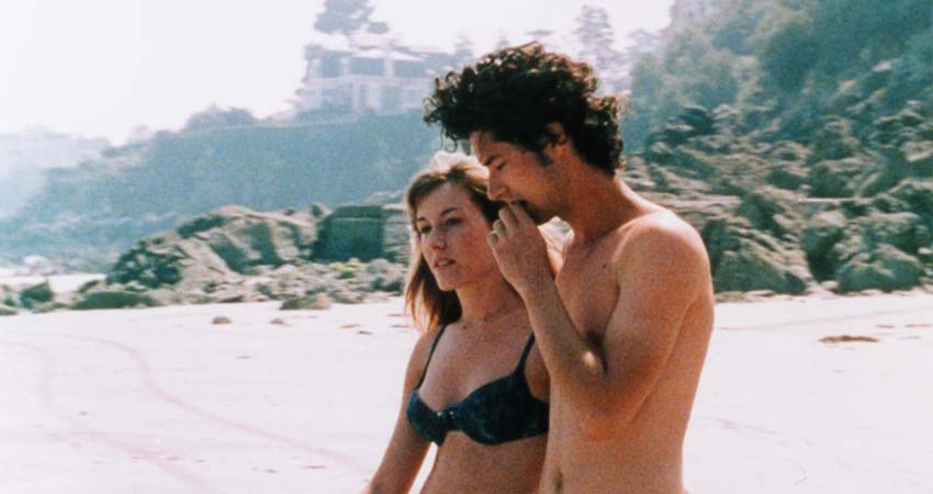 Un xic i una xica passejant per la platja