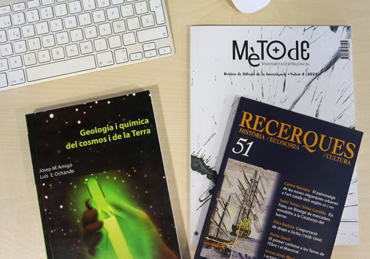 Llibres, revistes i altres publicacions acadèmiques damunt d'una taula al costat d'un teclat i un ratolí.