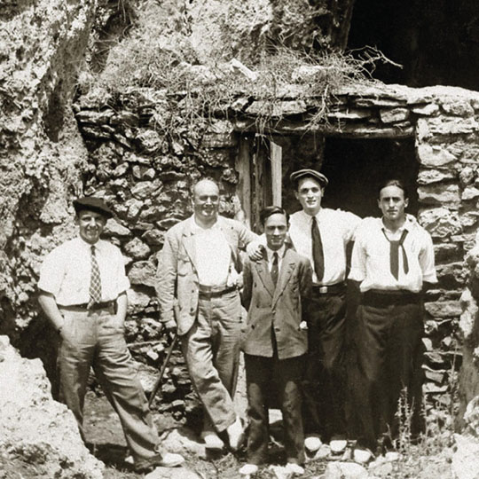 Five men in front of the door of a ruined building
