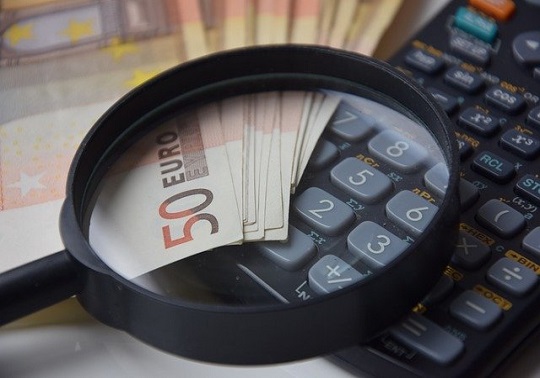 Imagen de dinero, una calculadora y una lupa