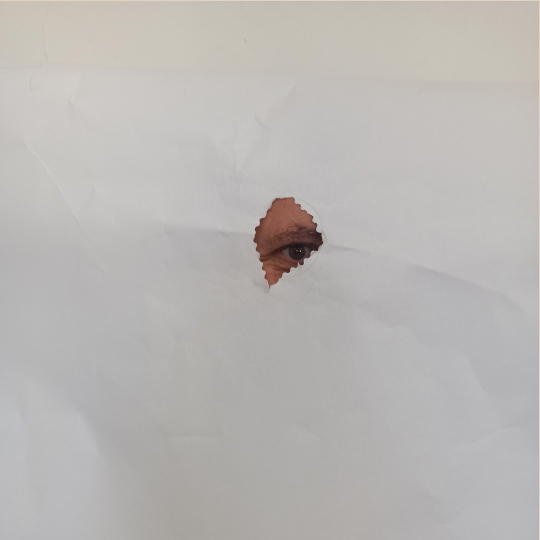 Ojo mirando por un agujero de un papel blanco