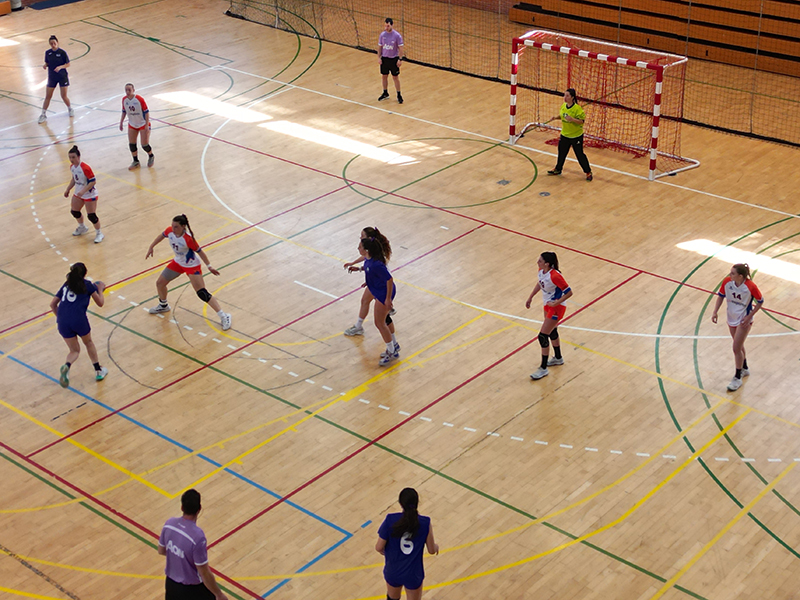 Equipo femenino de balonmano jugando en una cancha