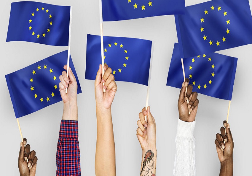 Unas manos sostienen diversas banderas de la Unión Europea