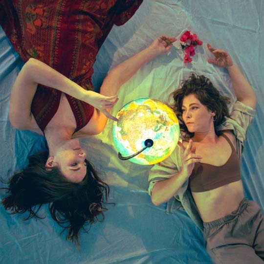 Dos mujeres tumbadas mirando un mapamundi