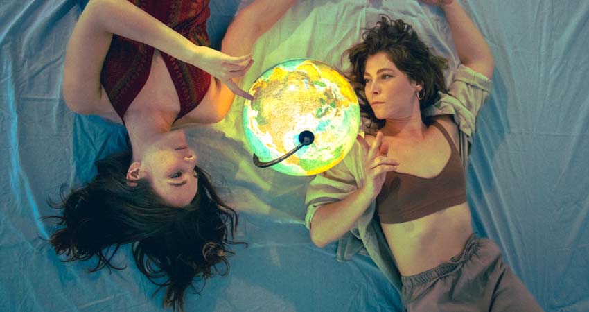 Two women lying down looking at a world map