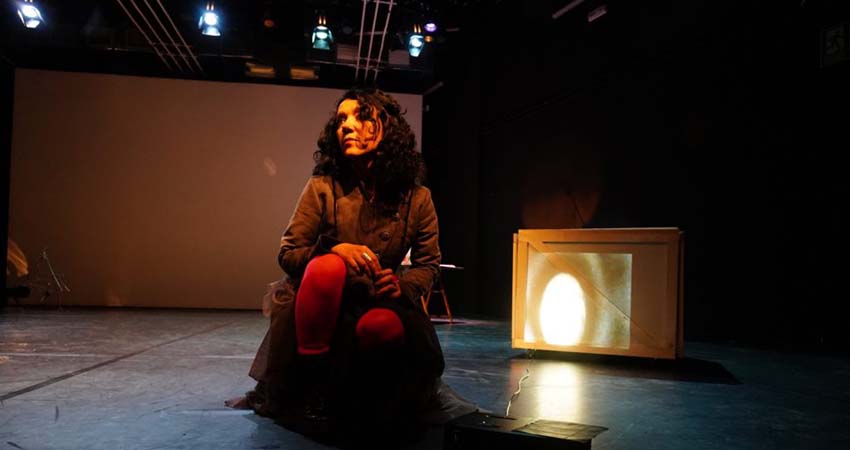 A woman kneeling in the middle of a stage