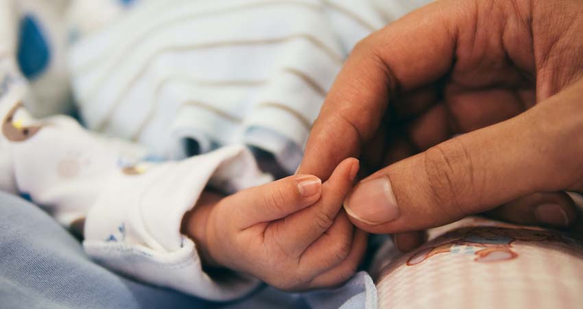 Una mano de adulto cogiendo la de un bebé