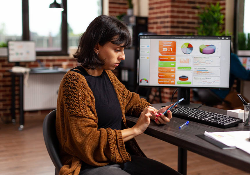 Una empresària consulta el mòbil en el treball.