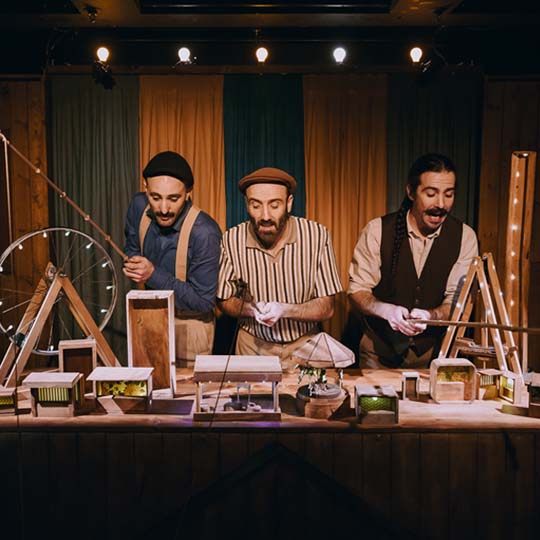 Tres hombres detrás de una mesa con la maqueta de una feria