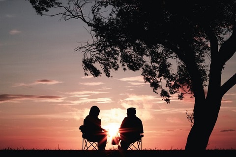Dos personas en sillas hablando delante de la puesta de sol