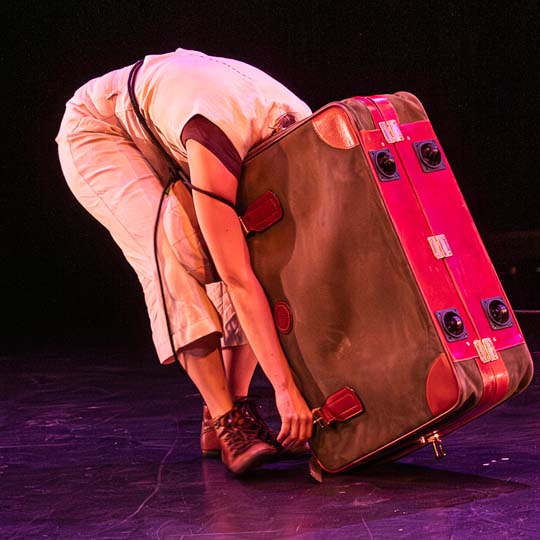 A person with his head inside a suitcase