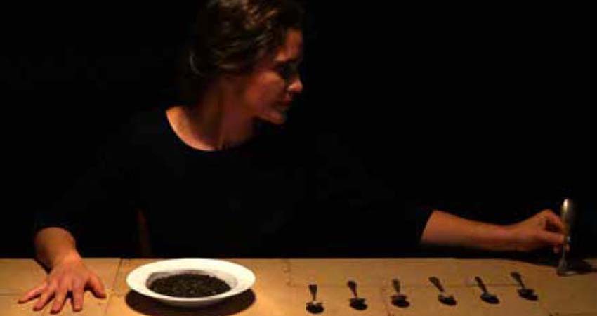 Actress sitting in front of a plate and kitchen cutlery