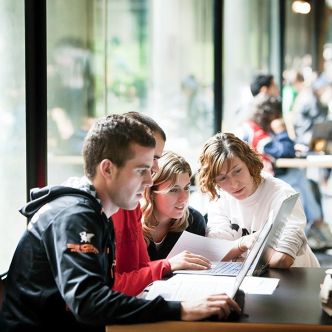 Becas y Ayudas - un grupo de alumnos observa la pantalla de un ordenador