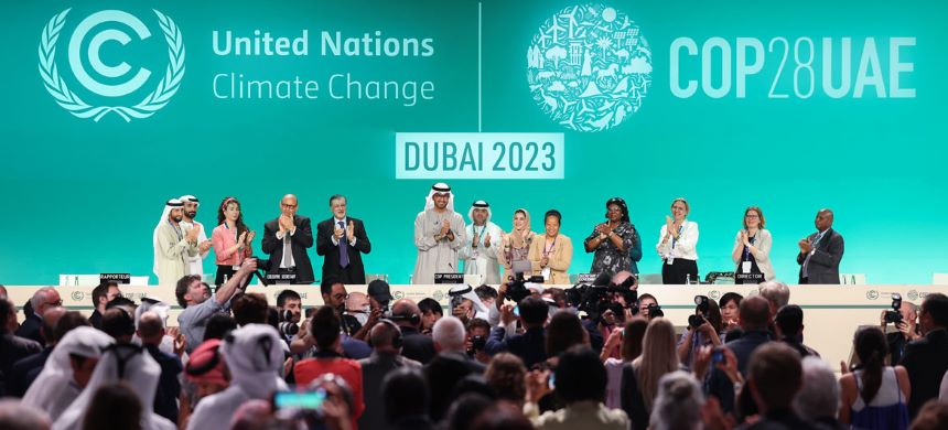 El president de la COP28, Sultan Jaber (centre), el representant de l'ONU per al clima, Simon Stiell (quart d'esquerra a dreta), i altres participants, dempeus en el podi durant la clausura de la conferència a Dubai