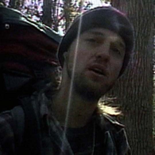 A man in a forest looking at the camera