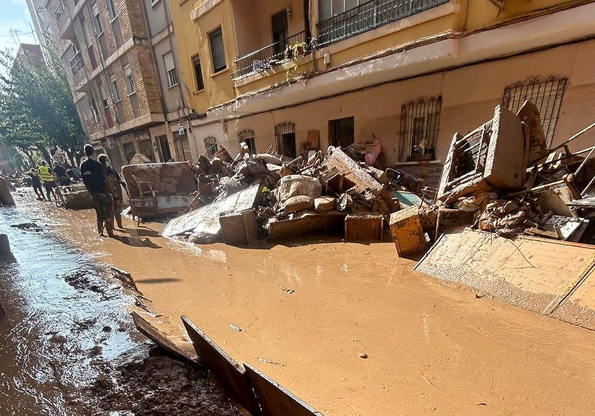 Street full of mud and waste with two volunteers wearing masks.