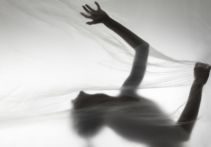 Silueta de un bailarín tras una tela transparente.