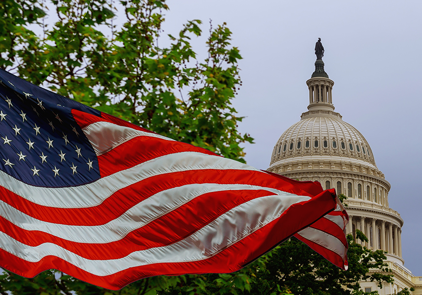 USA flag flying with Capitol dome in the background
