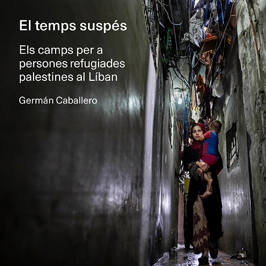 Una mujer carga con su hijo por una calle del campo de refugiados