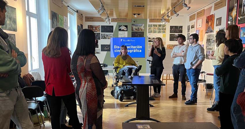 Group of people listening to a woman in a wheelchair
