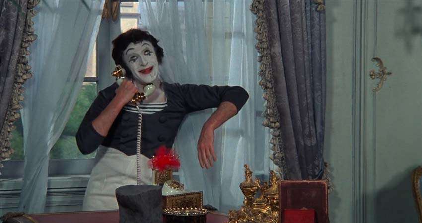 A man dressed as a clown talking on the phone
