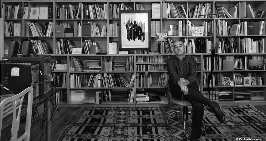 Alfonso de la Torre sentado delante de una estantería con libros