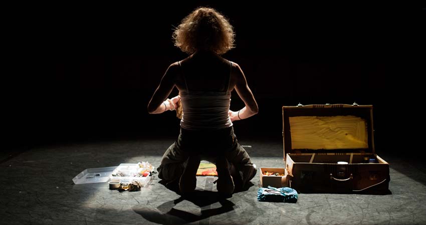 A woman kneeling packing her suitcase