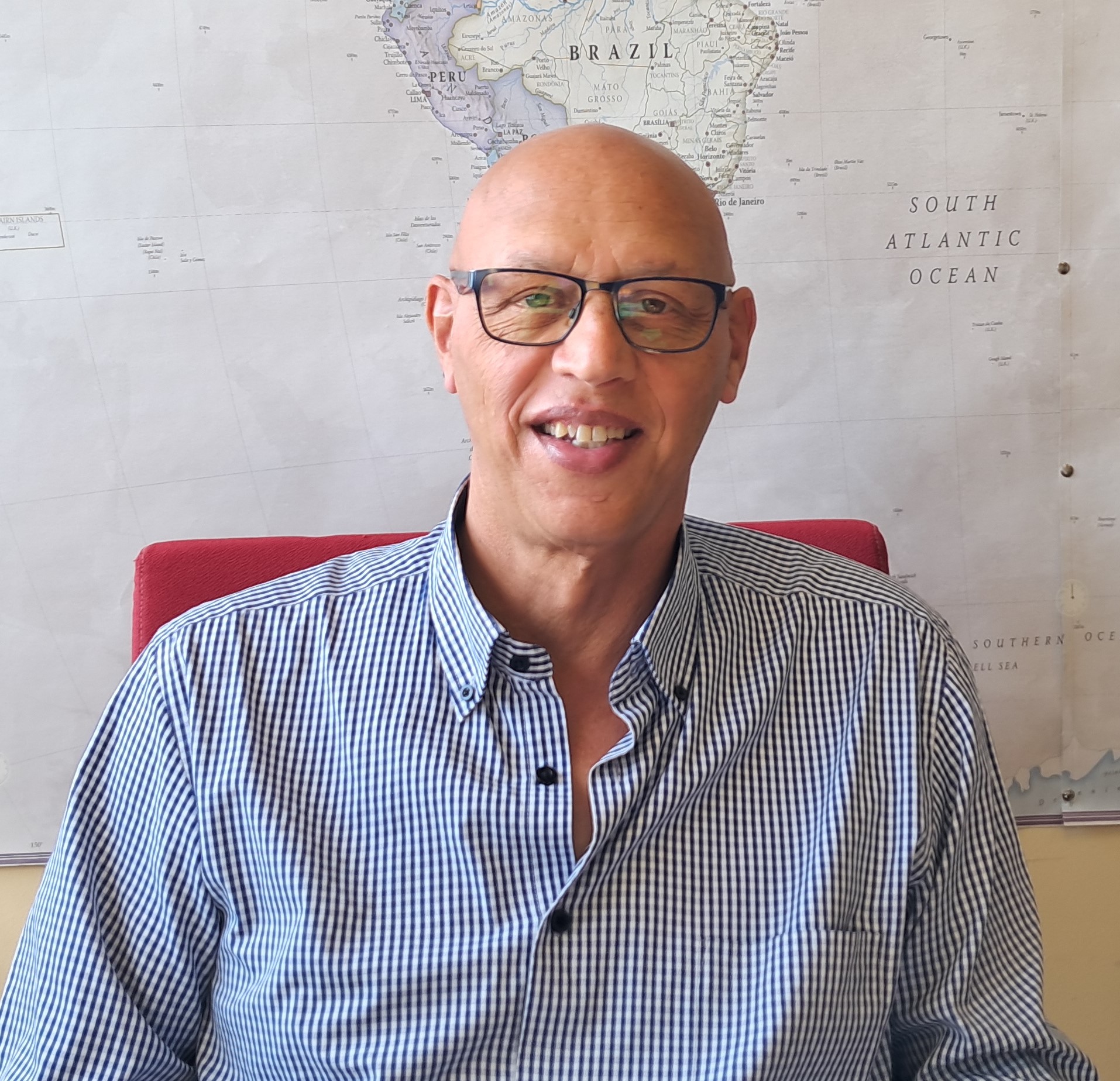 Un hombre con lentes sentado en una sillaDescripci�n generada autom�ticamente con confianza media
